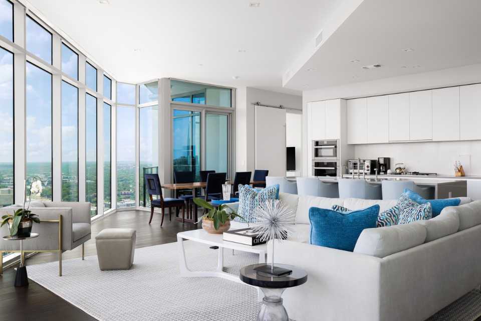 open concept living, dining room of penthouse condo with white walls, floor to ceiling views, and blue accents